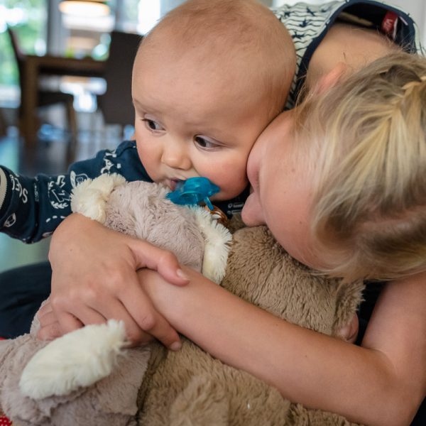 Tijdens deze fotosessie van groot gezin, krijgt kleine Jens dikke vette knuffels van zijn grote zus. Familie fotografie, Sandra Stokmans Fotografie